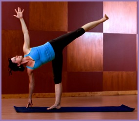 Young woman doing Half Moon Pose in a yoga studio